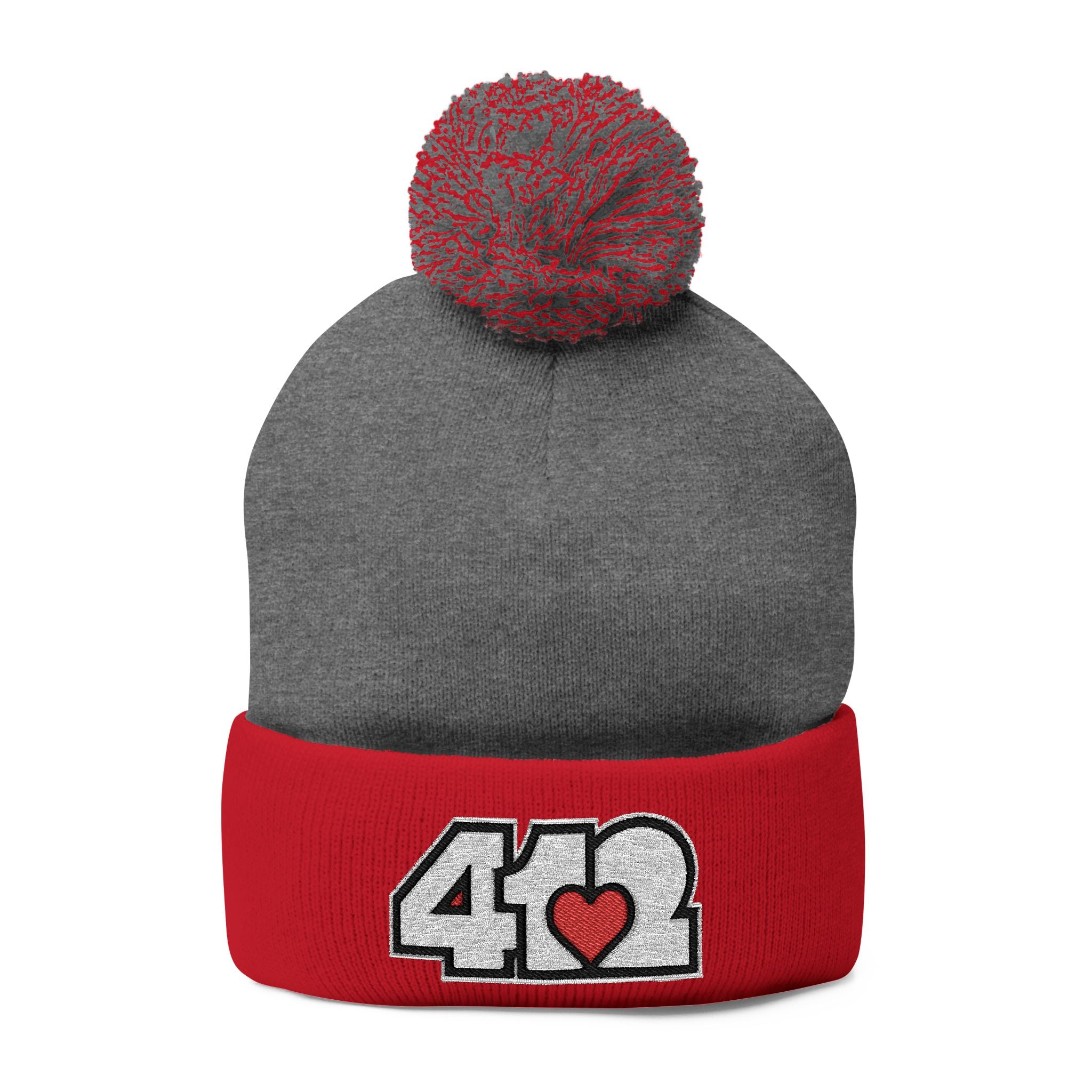 412 Tossle Cap | Embroidered White and Red Logo. Apparel Size: One size. Has soft acrylic knit, fold-over cuff, and one-size fit for winter comfort.