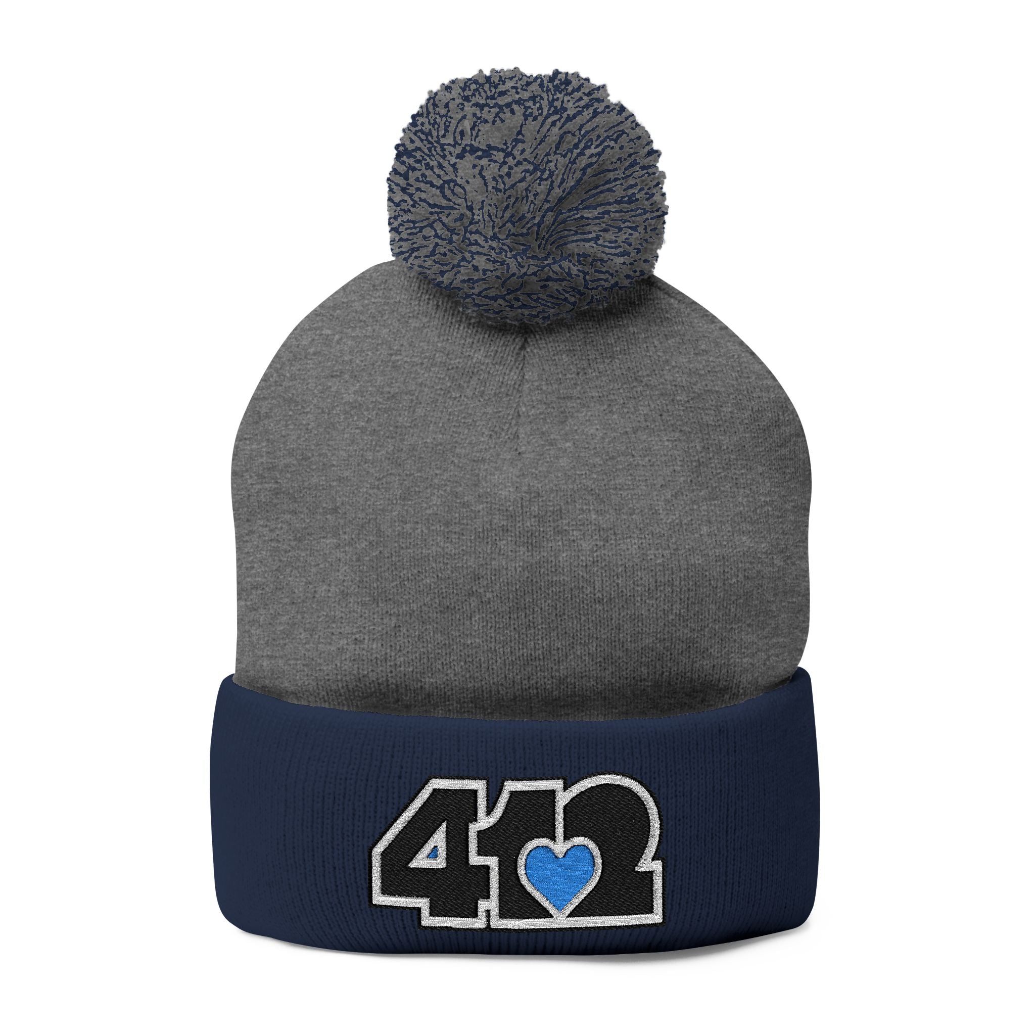 Cozy 412 Tossle Cap | Embroidered Black and Blue Logo. Apparel Color: Dark Heather Grey / navy. Has soft acrylic knit, fold-over cuff, and one-size fit for winter comfort.