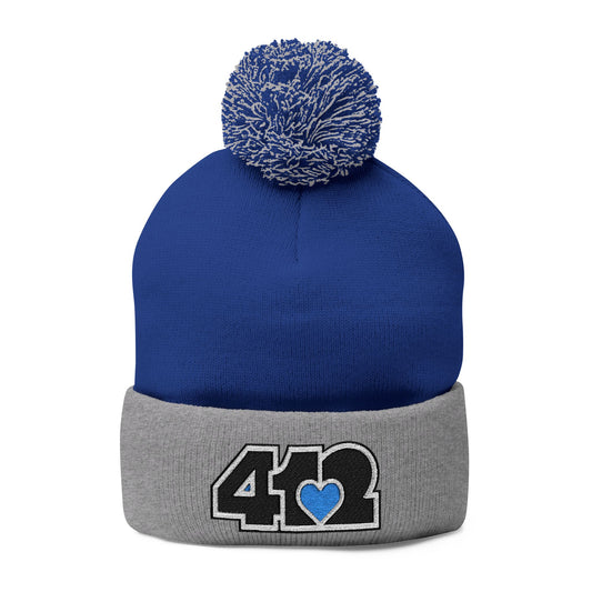 Cozy 412 Tossle Cap | Embroidered Black and Blue Logo. Apparel Color: Royal / Heather Grey. Has soft acrylic knit, fold-over cuff, and one-size fit for winter comfort.
