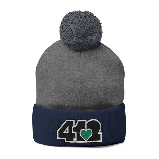 Cozy 412 Tossle Cap | Embroidered Black and Green Logo. Apparel Color: Dark Heather Grey / navy. Has soft acrylic knit, fold-over cuff, and one-size fit for winter comfort.