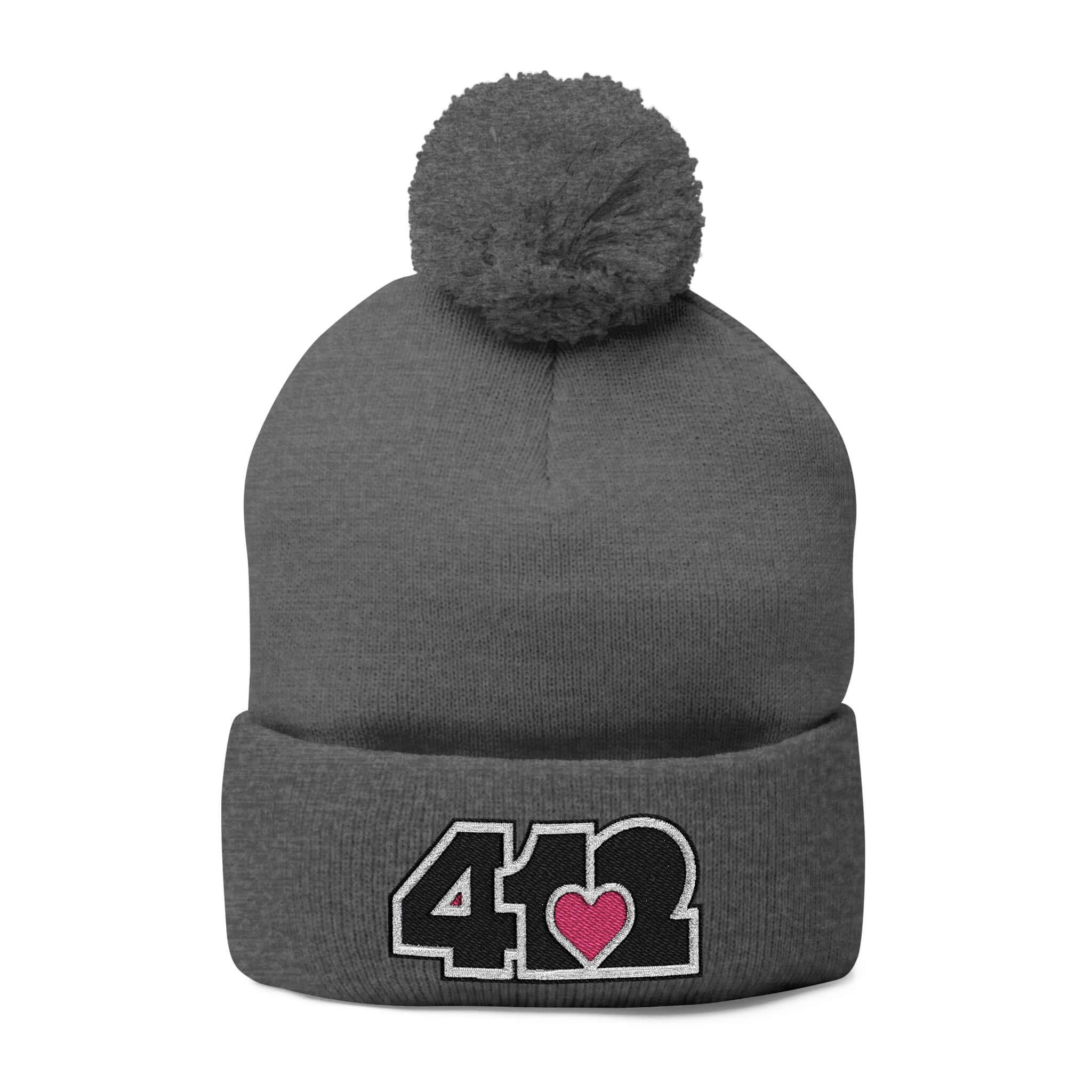 Cozy 412 Tossle Cap | Embroidered Black and Pink Logo. Apparel Color: Dark Heather Grey. Has soft acrylic knit, fold-over cuff, and one-size fit for winter comfort.
