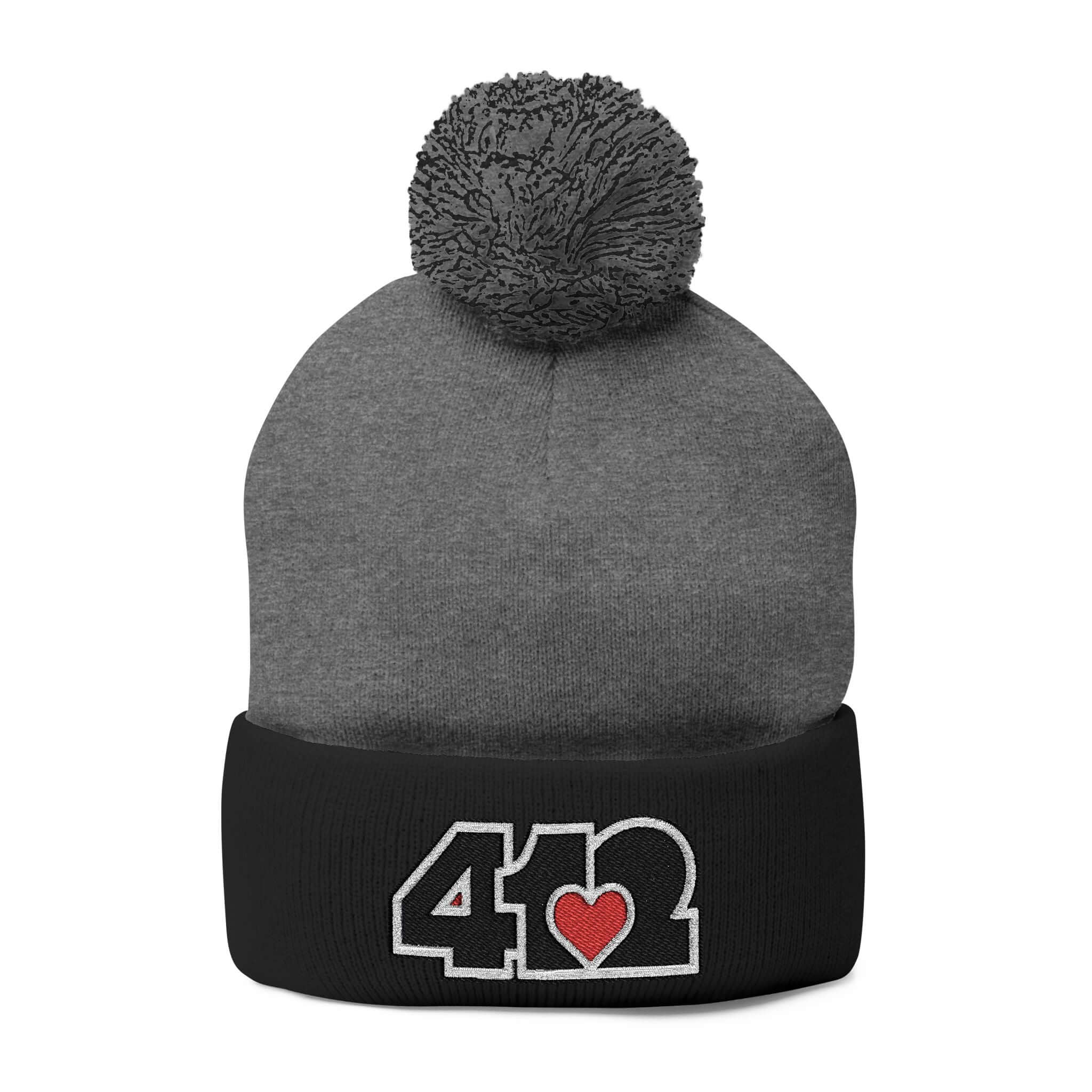 Cozy 412 Tossle Cap | Embroidered Black and Red Logo. Apparel Color: Dark Heather Grey / Black. Has soft acrylic knit, fold-over cuff, and one-size fit for winter comfort.