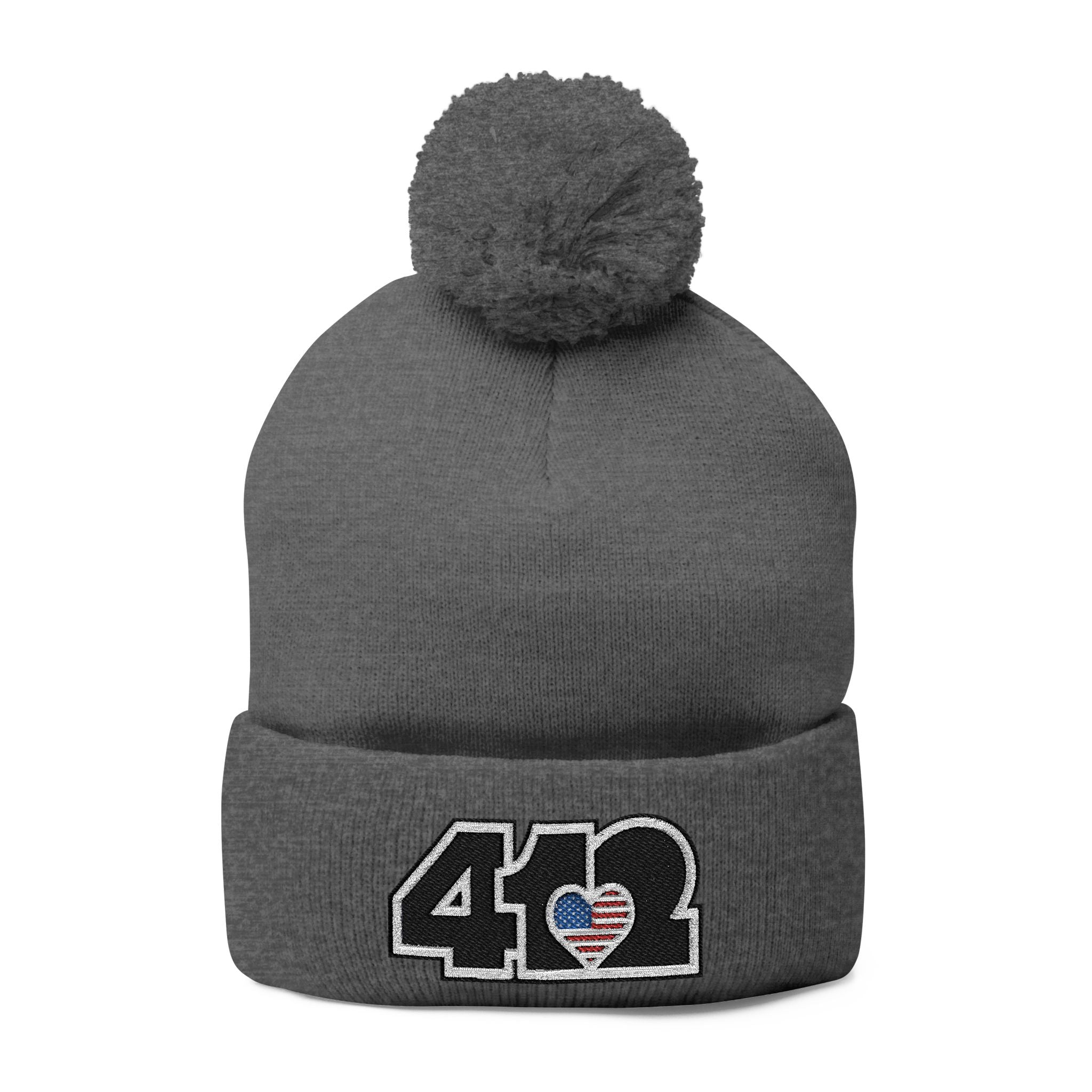 412 Tossle Cap | Embroidered Stars & Stripes Black Logo. Apparel Color: Dark Heather Grey. Has soft acrylic knit, fold-over cuff, and one-size fit for winter comfort.