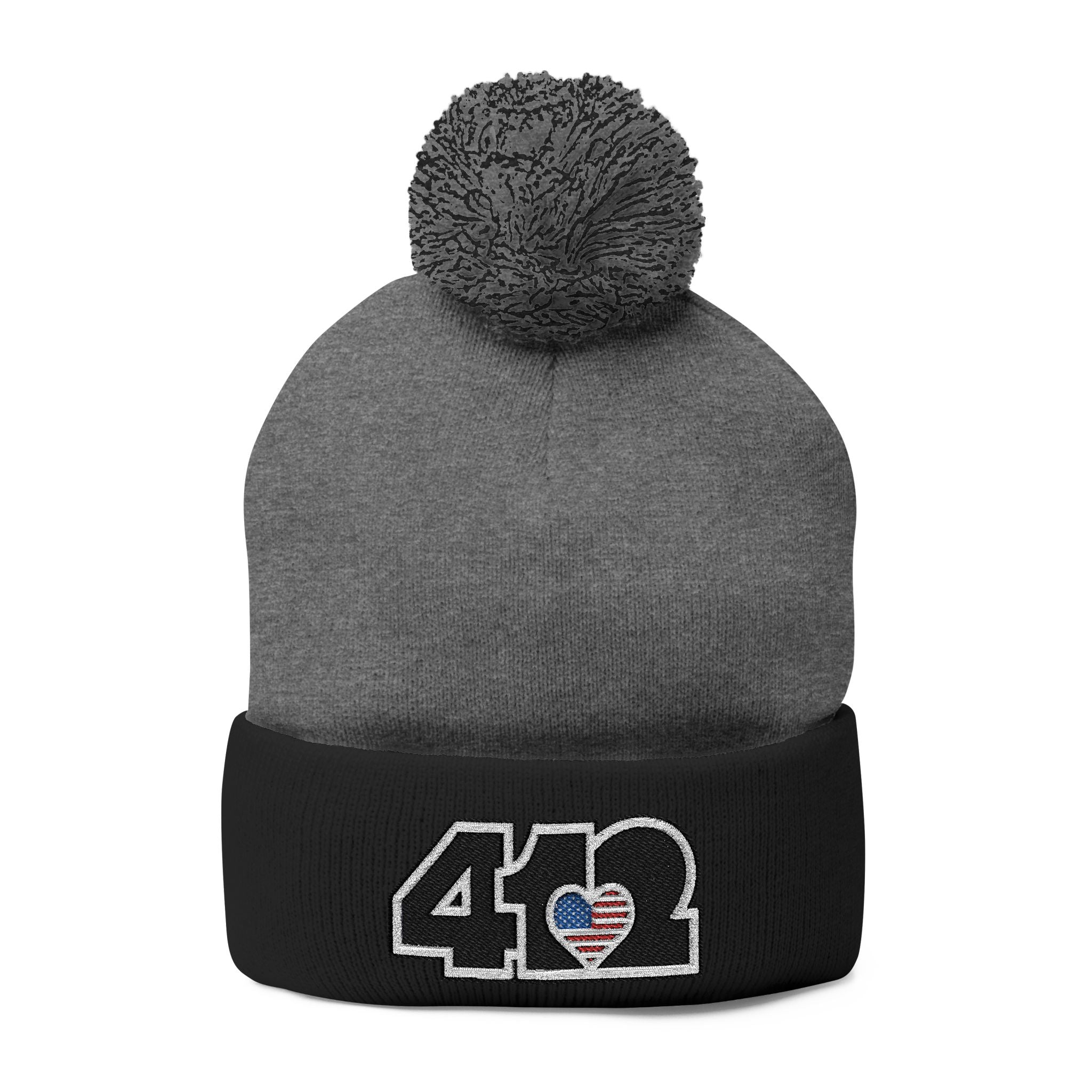 412 Tossle Cap | Embroidered Stars & Stripes Black Logo. Apparel Color: Dark Heather Grey / Black. Has soft acrylic knit, fold-over cuff, and one-size fit for winter comfort.