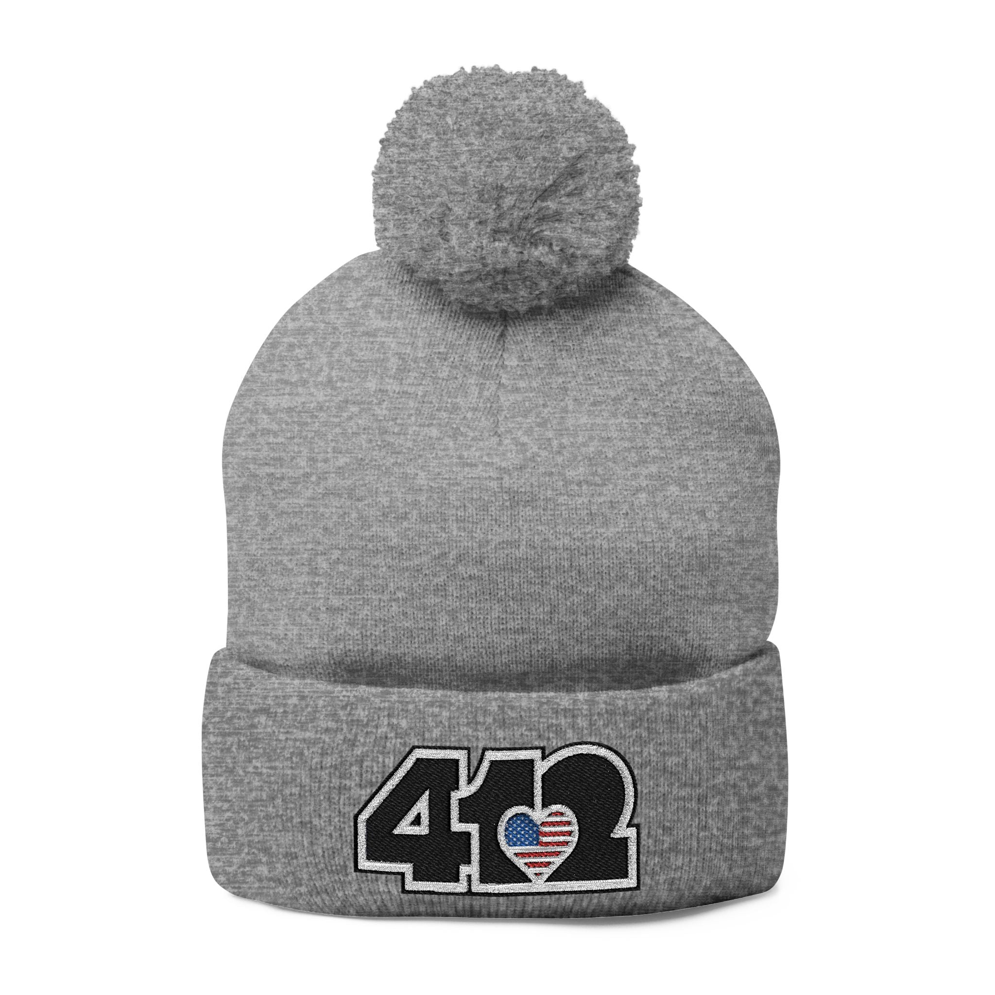 412 Tossle Cap | Embroidered Stars & Stripes Black Logo. Apparel Color: Heather Grey. Has soft acrylic knit, fold-over cuff, and one-size fit for winter comfort.