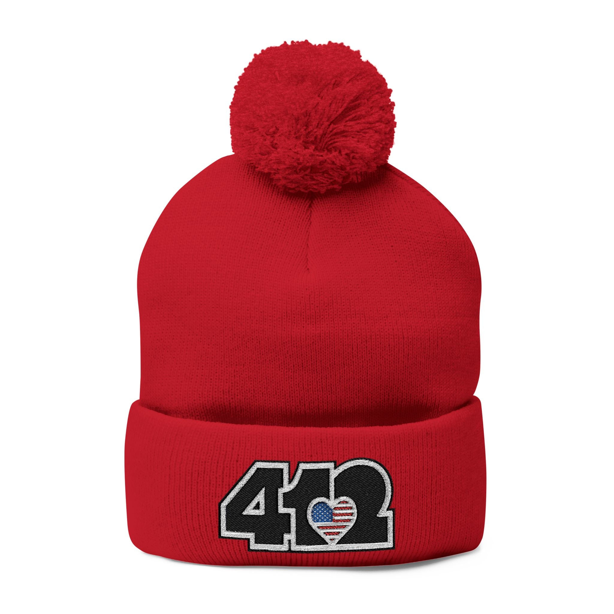 412 Tossle Cap | Embroidered Stars & Stripes Black Logo. Apparel Color: Red. Has soft acrylic knit, fold-over cuff, and one-size fit for winter comfort.