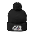 412 Tossle Cap | Embroidered Stars & Stripes White Logo. Apparel Color: Black. Has soft acrylic knit, fold-over cuff, and one-size fit for winter comfort.
