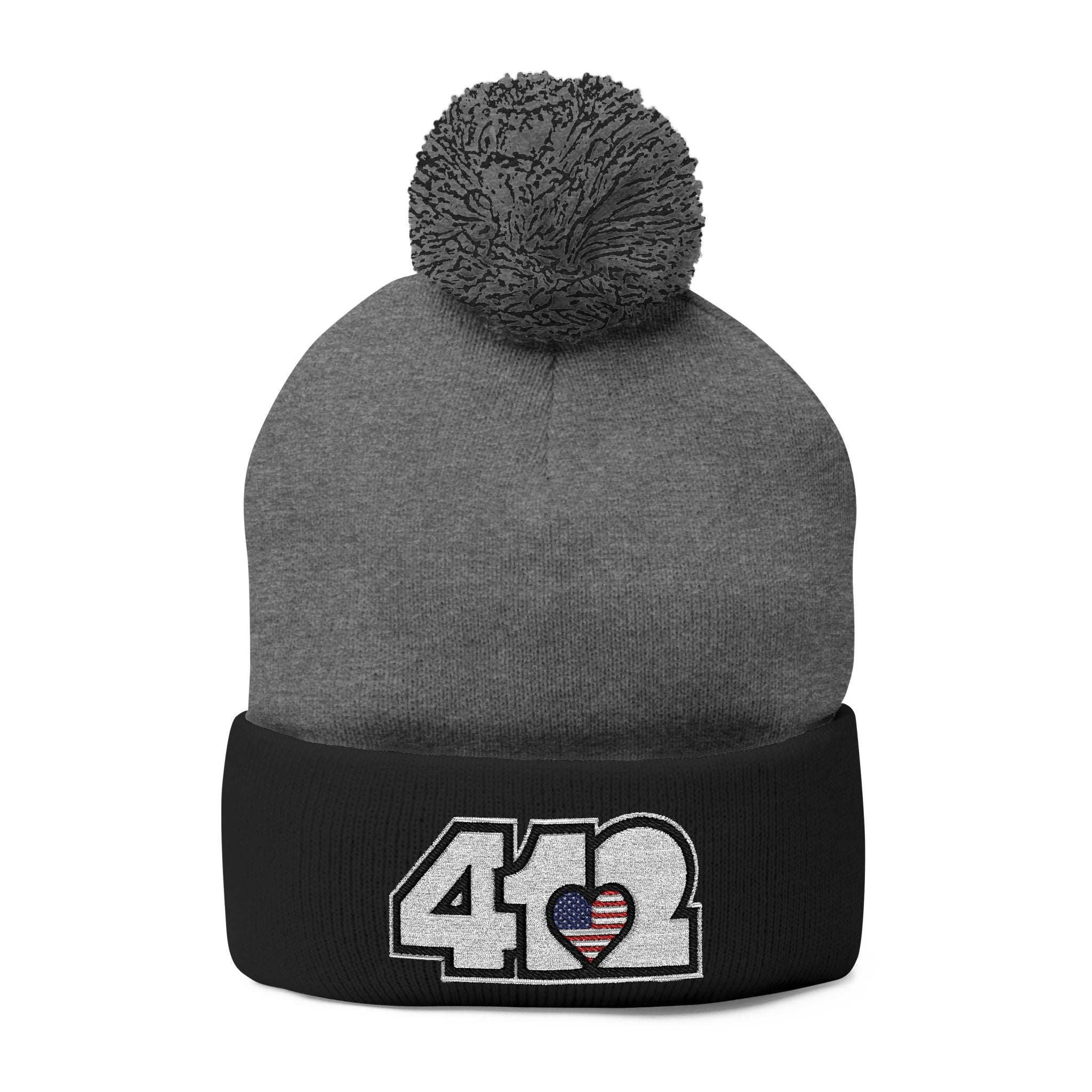 412 Tossle Cap | Embroidered Stars & Stripes White Logo. Apparel Color: Dark Heather Grey / Black. Has soft acrylic knit, fold-over cuff, and one-size fit for winter comfort.