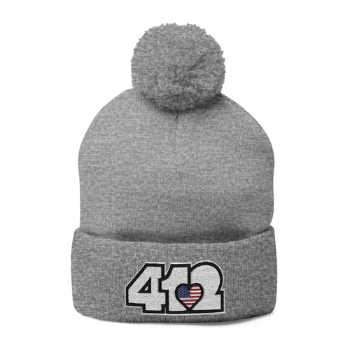 412 Tossle Cap | Embroidered Stars & Stripes White Logo. Apparel Color: Heather Grey. Has soft acrylic knit, fold-over cuff, and one-size fit for winter comfort.