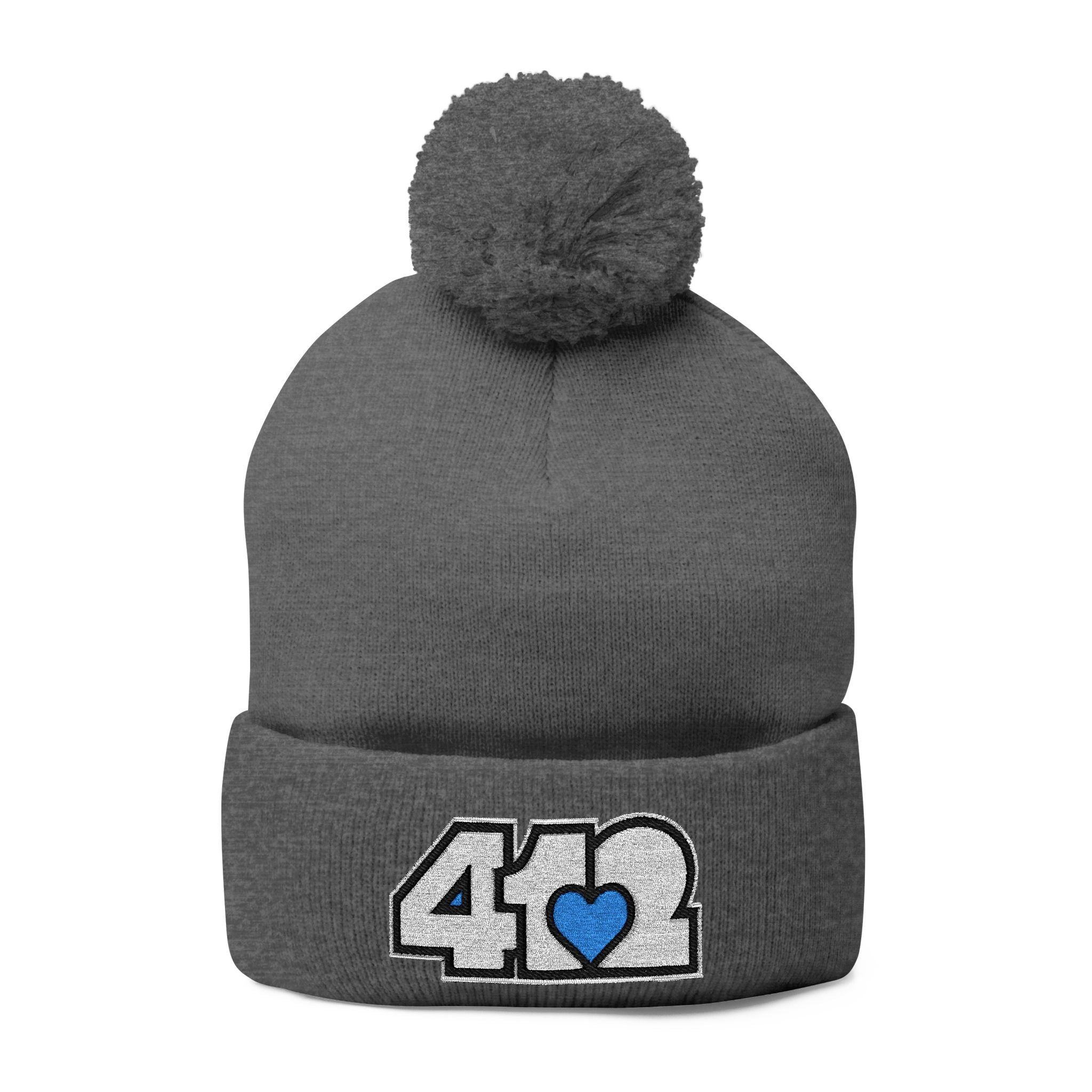 412 Tossle Cap | Embroidered White and Blue Logo. Apparel Color: Dark Heather Grey. Has soft acrylic knit, fold-over cuff, and one-size fit for winter comfort.