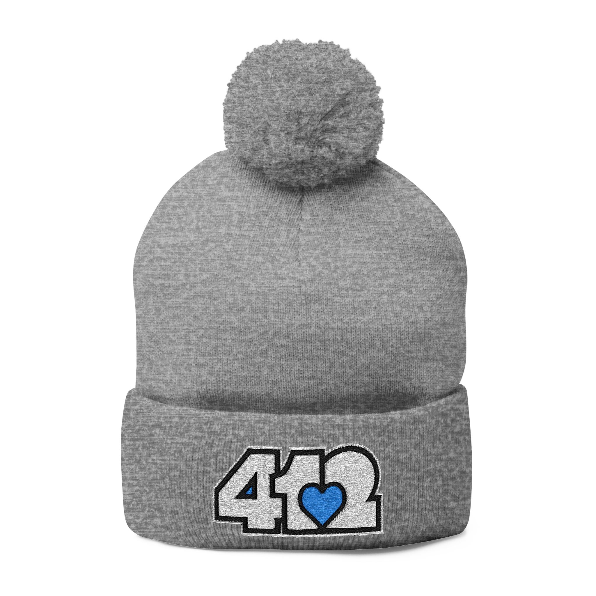 412 Tossle Cap | Embroidered White and Blue Logo. Apparel Color: Heather Grey. Has soft acrylic knit, fold-over cuff, and one-size fit for winter comfort.