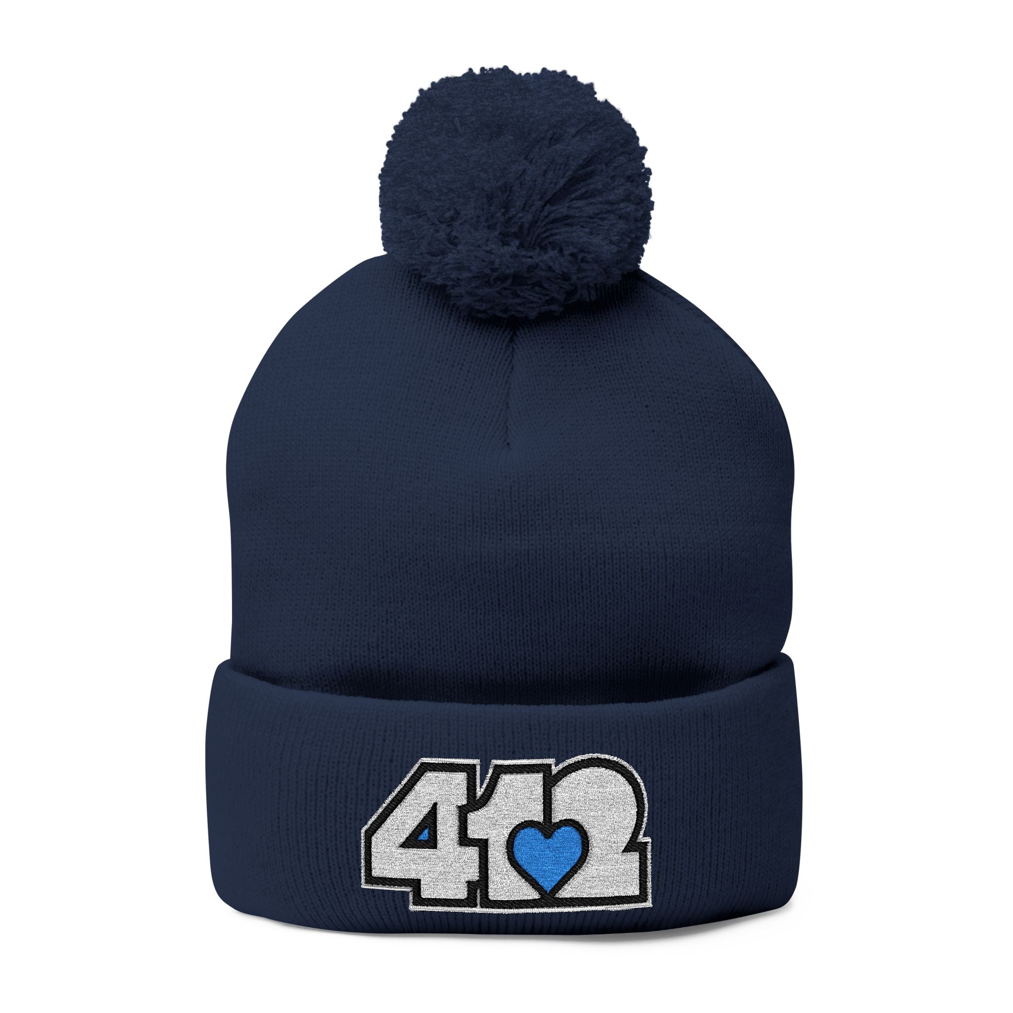 412 Tossle Cap | Embroidered White and Blue Logo. Apparel Color: Navy. Has soft acrylic knit, fold-over cuff, and one-size fit for winter comfort.
