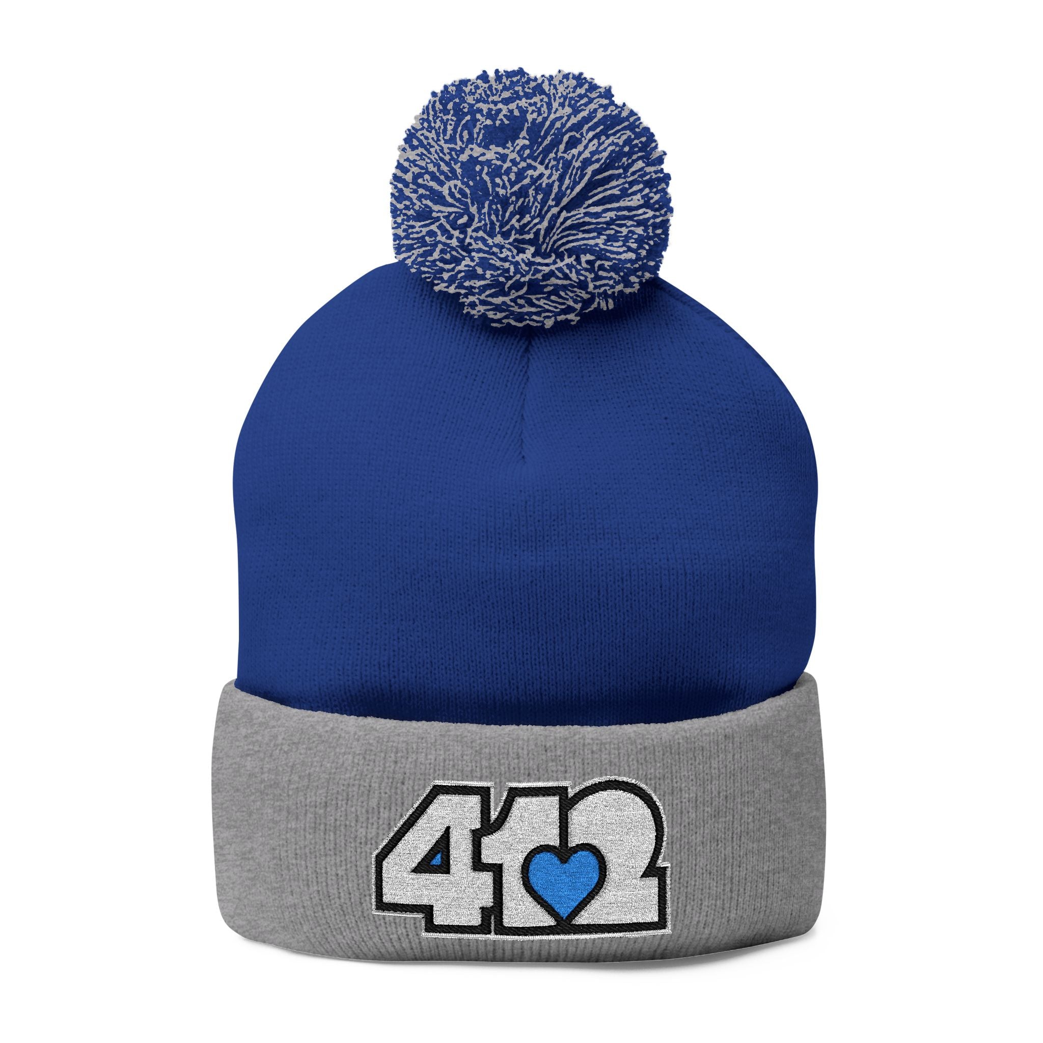412 Tossle Cap | Embroidered White and Blue Logo. Apparel Color: Royal / Heather Grey. Has soft acrylic knit, fold-over cuff, and one-size fit for winter comfort.