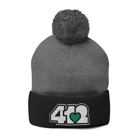 Cozy 412 Tossle Cap | Embroidered White and Green Logo. Apparel Color: Dark Heather Grey / Black. Has soft acrylic knit, fold-over cuff, and one-size fit for winter comfort.