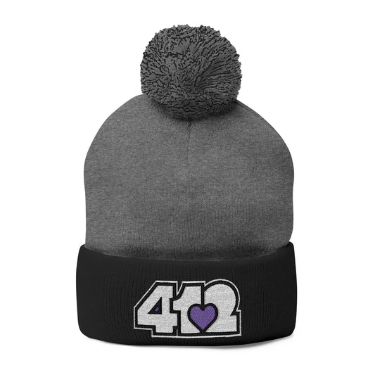 Cozy 412 Tossle Cap | Embroidered White and Purple Logo. Apparel Color: Dark Heather Grey / Black. Has soft acrylic knit, fold-over cuff, and one-size fit for winter comfort.