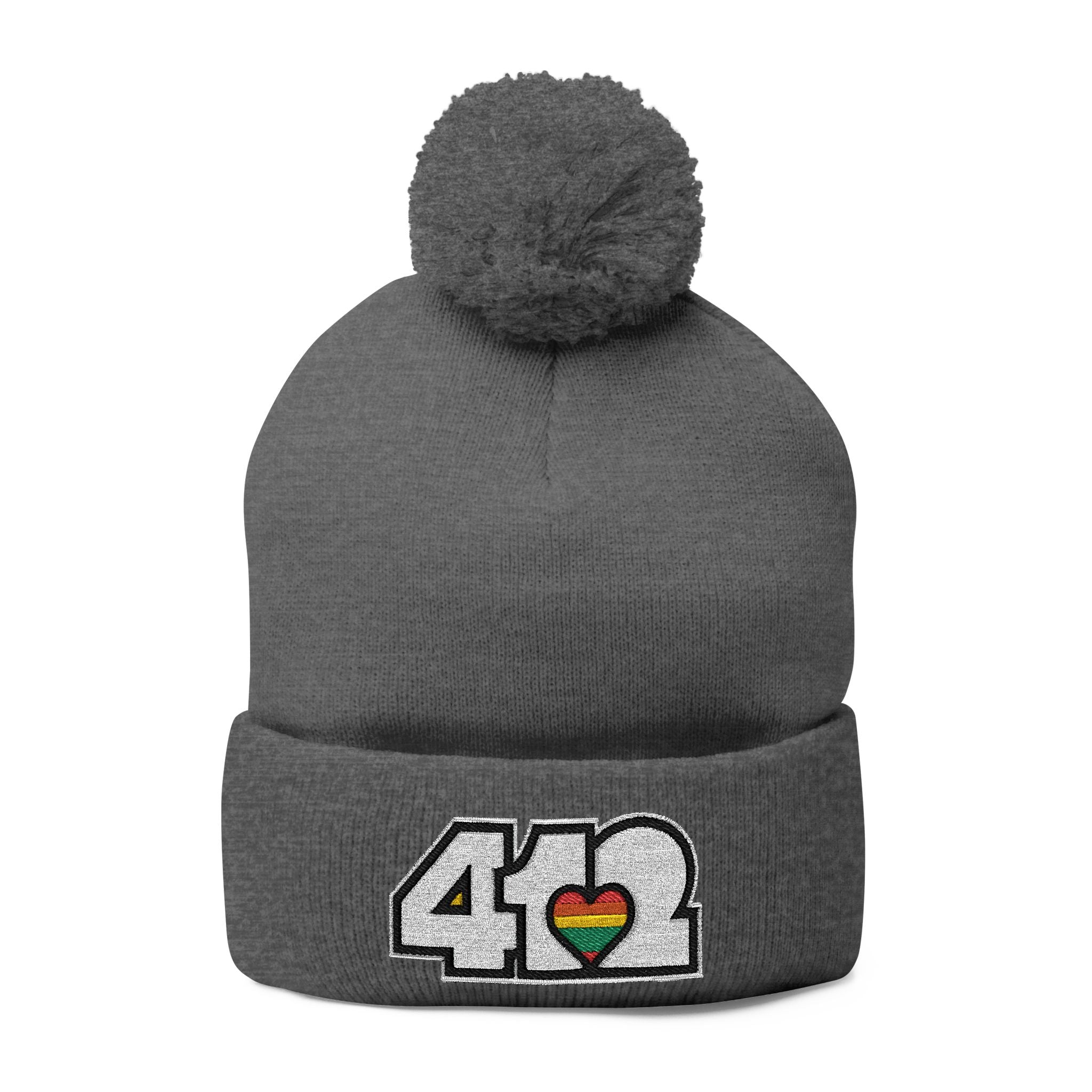 412 Tossle Cap | Embroidered White and Rainbow Logo. Apparel Color: Dark Heather Grey. Has soft acrylic knit, fold-over cuff, and one-size fit for winter comfort.