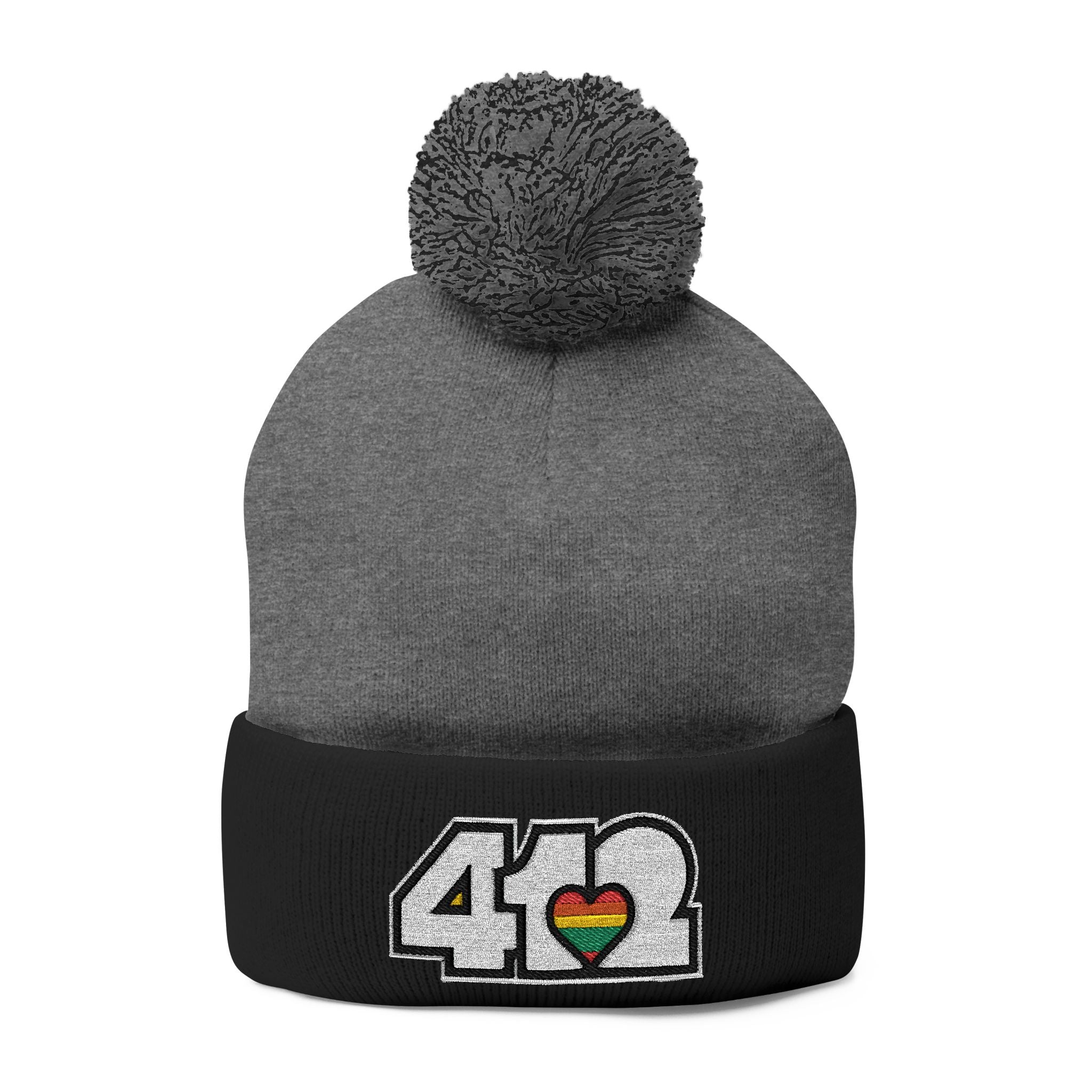 412 Tossle Cap | Embroidered White and Rainbow Logo. Apparel Color: Dark Heather Grey / Black. Has soft acrylic knit, fold-over cuff, and one-size fit for winter comfort.