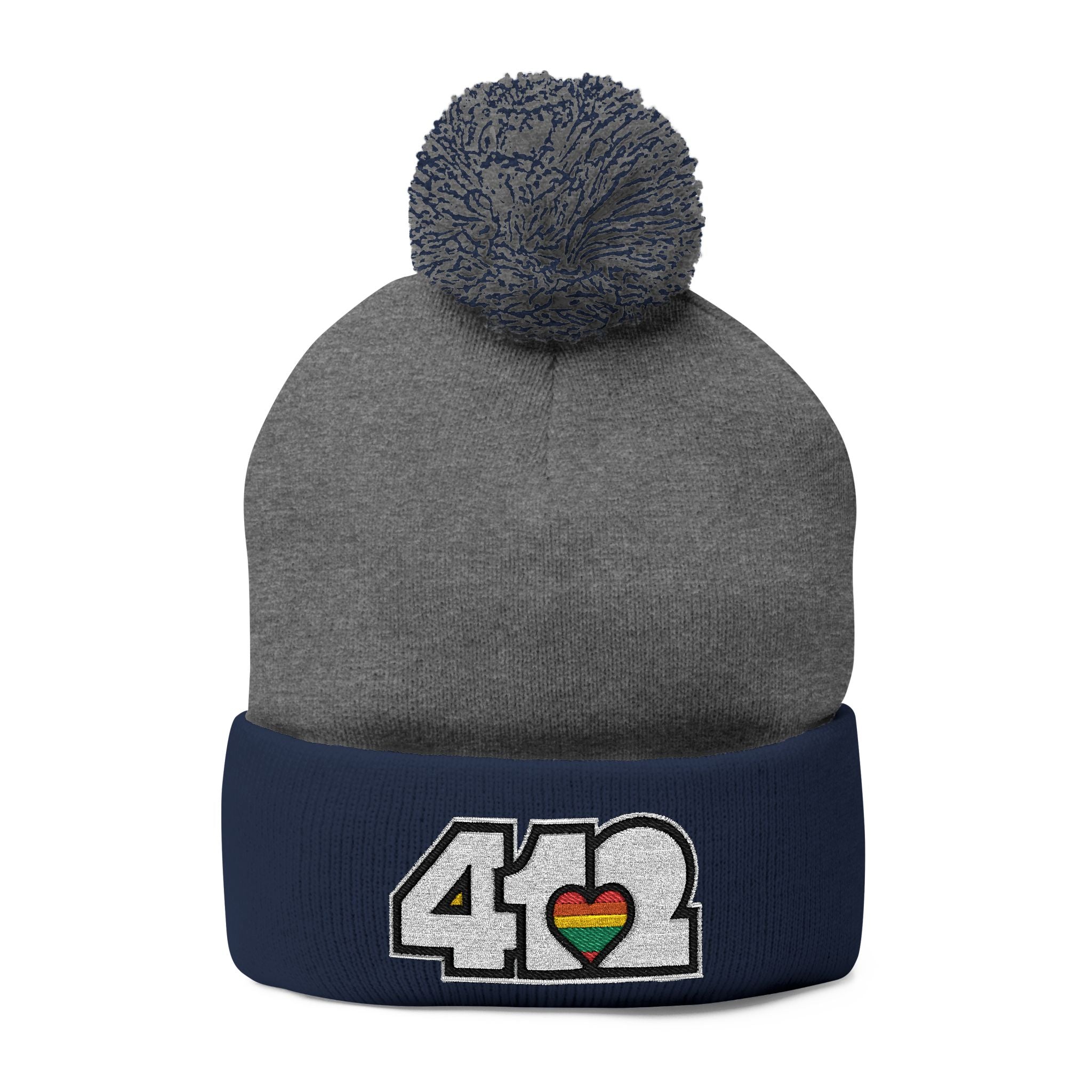 412 Tossle Cap | Embroidered White and Rainbow Logo. Apparel Color: Dark Heather Grey / Navy. Has soft acrylic knit, fold-over cuff, and one-size fit for winter comfort.