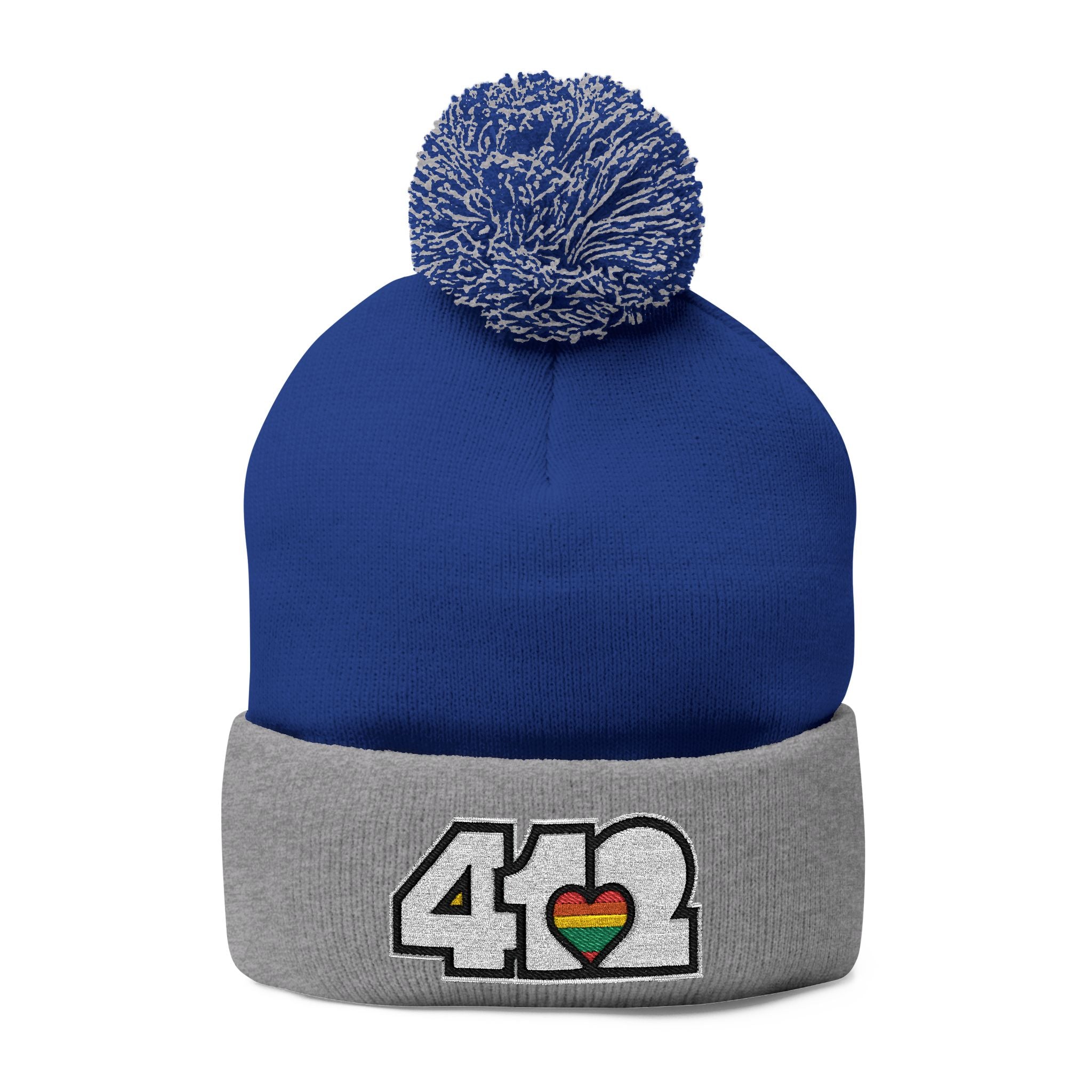 412 Tossle Cap | Embroidered White and Rainbow Logo. Apparel Color: Royal / Heather Grey. Has soft acrylic knit, fold-over cuff, and one-size fit for winter comfort.