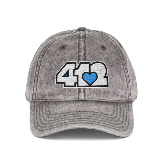 Pittsburgh Vintage Hat | Embroidered White and Blue 412 Logo. Apparel Color: Charcoal Grey. A relaxed fit, cotton twill fabric, adjustable buckle, and washed-out finish look.