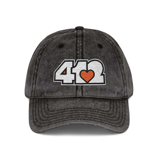 Pittsburgh Vintage Hat | Embroidered White and Orange 412 Logo. Apparel Color: Black. A relaxed fit, cotton twill fabric, adjustable buckle, and washed-out finish look.