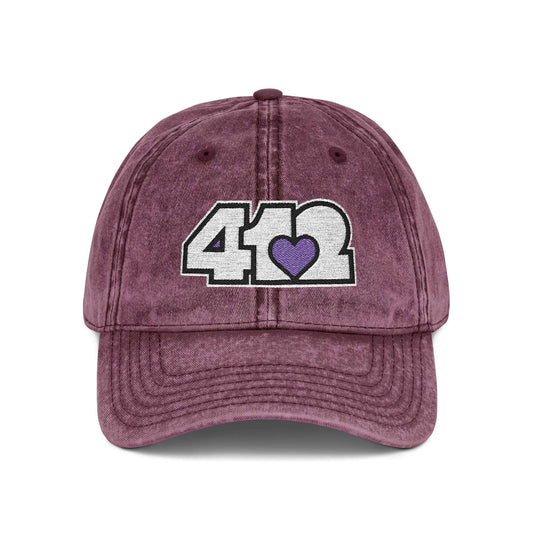 Pittsburgh Vintage Hat | Embroidered White and Purple 412 Logo. Apparel Color: Maroon. A relaxed fit, cotton twill fabric, adjustable buckle, and washed-out finish look.